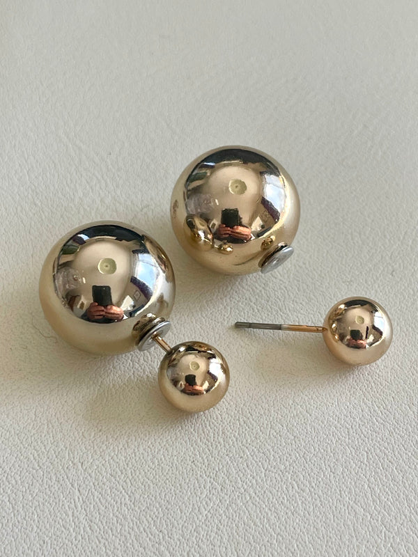 Pair of gold spherical earrings on a light gray background