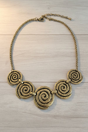 Gold spiral necklace on a dark marble surface