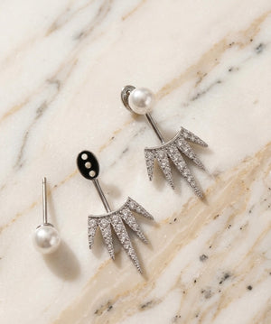 Silver earrings with pearl accents on a marble surface