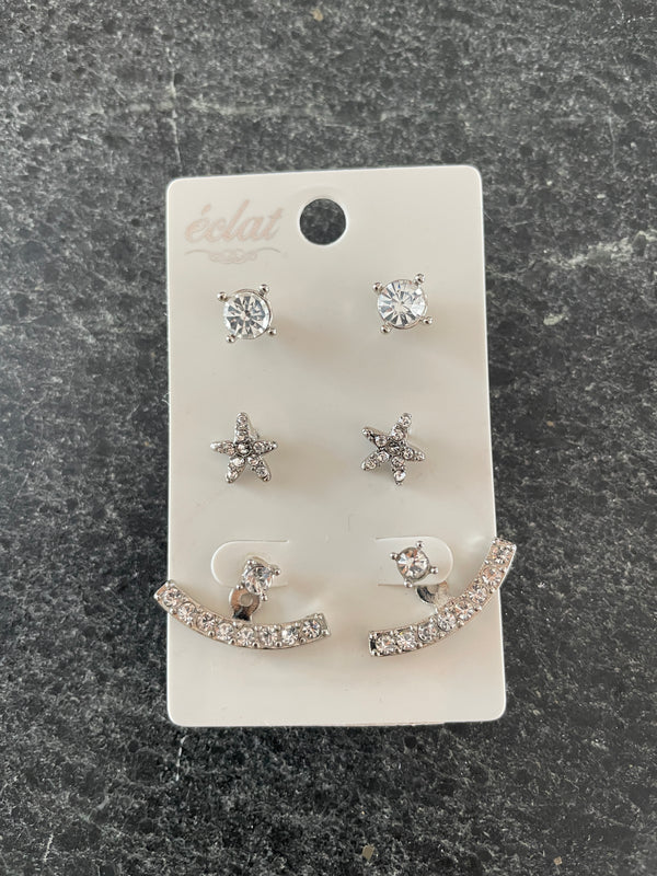 Set of silver earrings on a display card against a dark stone background