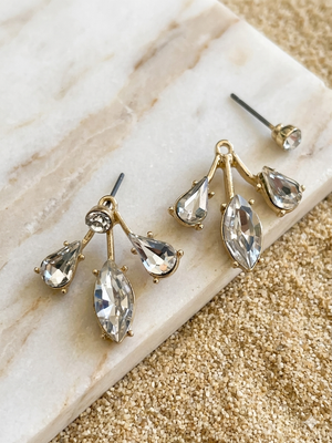 Gold earrings with clear stones on a marble surface