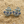 Charger l'image dans la galerie, Anchor-shaped earrings with blue accents on a sandy surface
