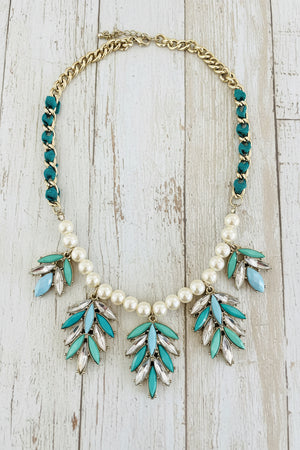 Necklace with turquoise leaves and pearls on a dark surface