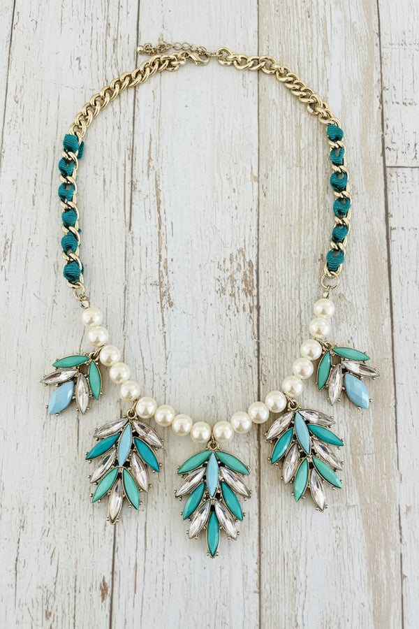 Necklace with turquoise leaves and pearls on a dark surface