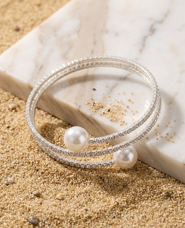 Silver bracelet with pearls on a marble surface with sand
