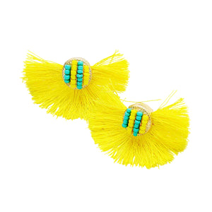 Yellow tassel earrings with turquoise beads on a light gray background