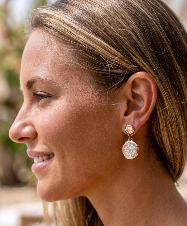 Close-up of a woman wearing a gold earring with a blurred natural background