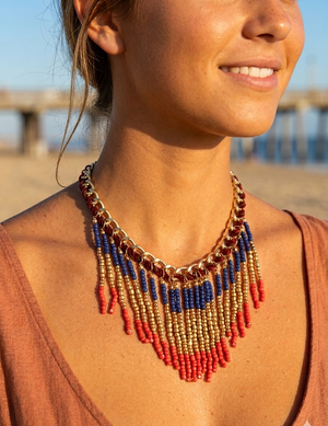Woman wearing a colorful beaded necklace with a blurred beach background