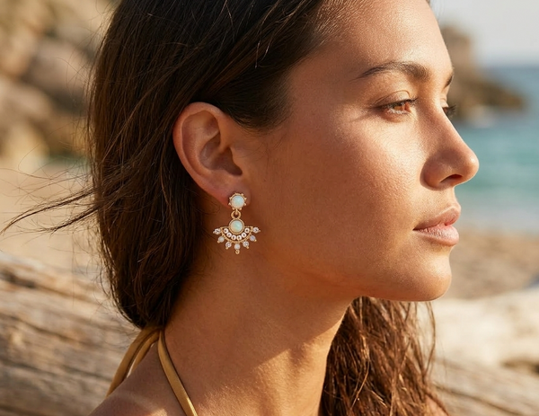 Woman wearing earrings with a blurred beach background