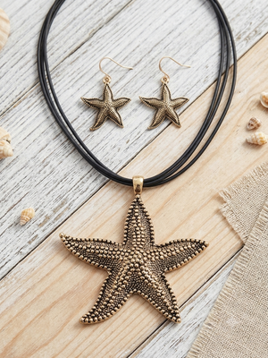 Starfish-shaped jewelry set on a wooden surface with shells.
