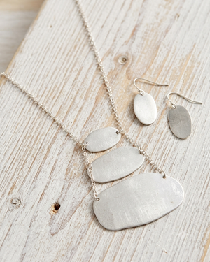 Silver necklace and earrings on a wooden surface