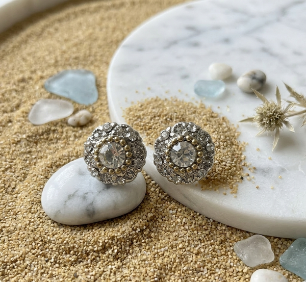 Silver earrings with gemstones on a sand and stone surface