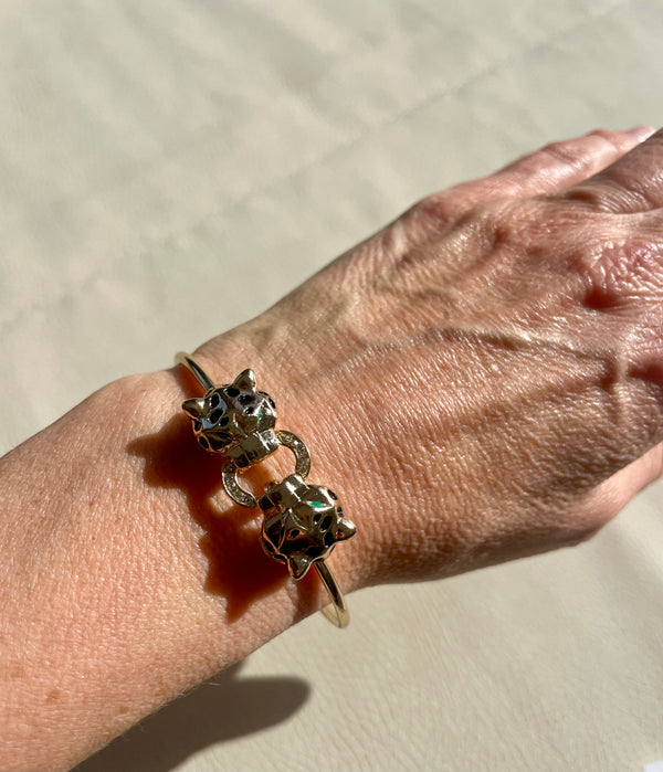 Gold bracelet with cat-shaped charms on a wrist against a neutral background