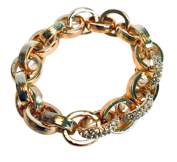 Gold chain bracelet with diamond accents on a light pink background