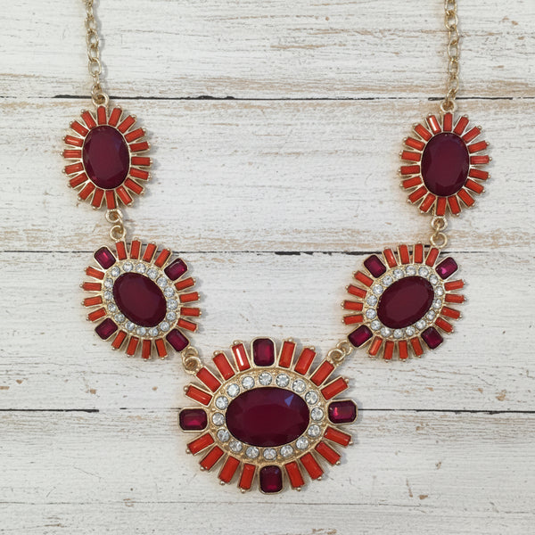 Ornate earrings with red and gold design on a white background