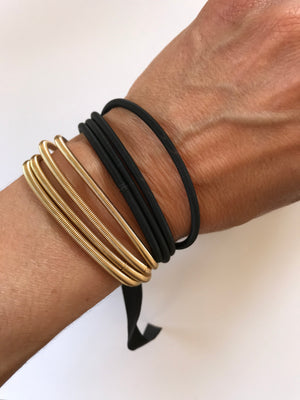 Gold bracelets on a wrist with a white background