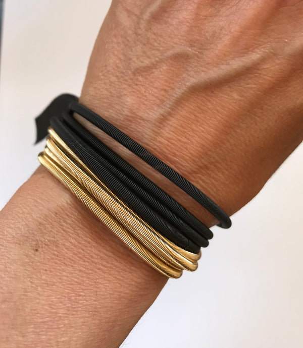 Close-up of a wrist wearing black and gold hair ties on a plain background