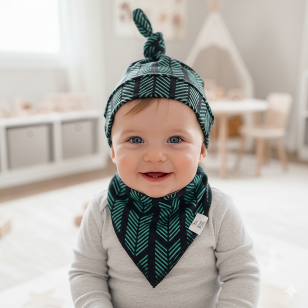 Baby wearing a green and black patterned hat and bib indoors.