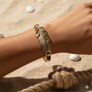 Gold feather bracelet on a wrist with a sandy background