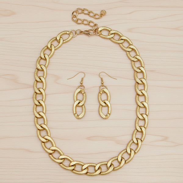 A gold-tone jewelry set featuring a chunky chain-link necklace and matching drop earrings with textured oval links, displayed on a clean white background.