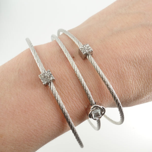 Silver bracelets with star-shaped charms on a wrist against a white background