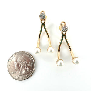 Gold earrings with pearl-like beads next to a quarter on a white background