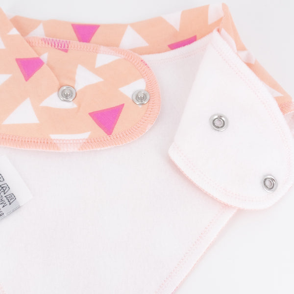 Baby bib with geometric pattern and white shirt with pink trim on a white background
