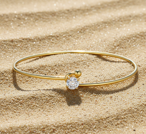 Gold bracelet with a diamond on a sandy background