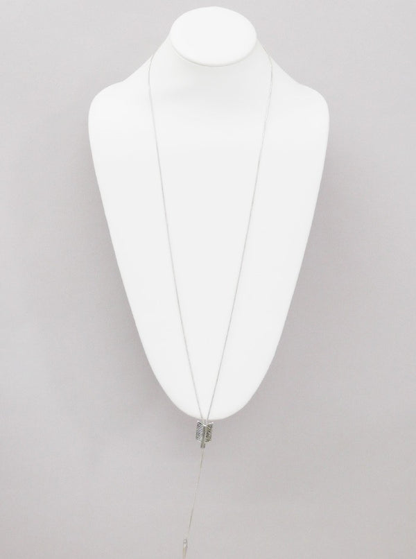 White necklace on a mannequin bust against a gray background