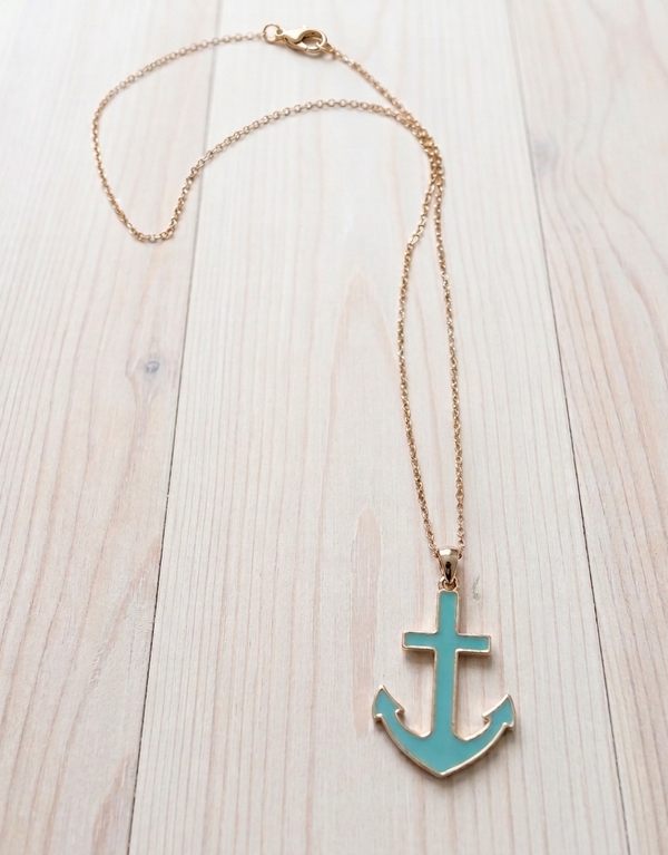 Necklace with a turquoise anchor pendant on a light wooden surface