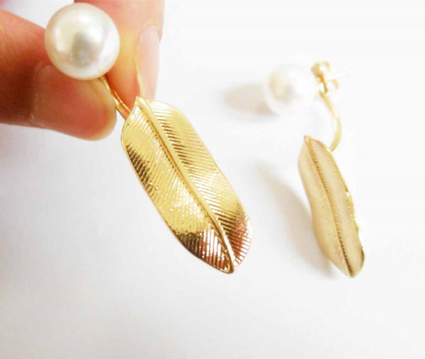 Gold feather-shaped earrings with pearls on a white background