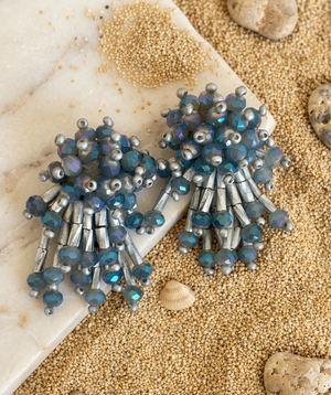 Pair of silver and blue beaded earrings on a textured surface