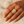 Load image into Gallery viewer, Hand wearing a gold ring with gemstones on a beige fabric background

