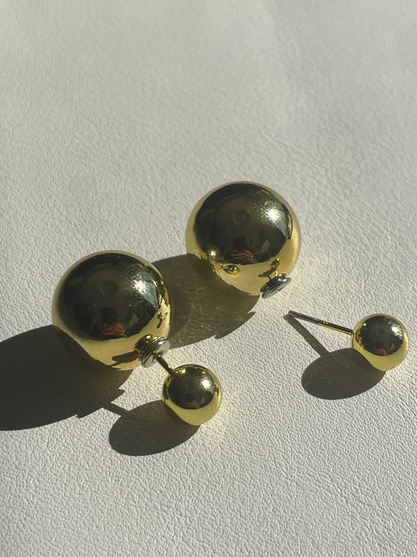 Gold earrings with round components on a light gray background