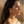 Load image into Gallery viewer, Woman in a white off-shoulder top standing in a desert-like setting with sand and palm leaves.

