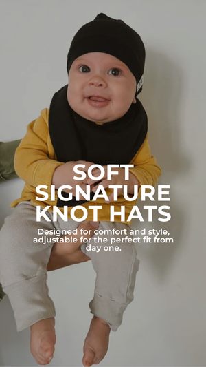 Baby wearing a black knot hat with text about soft signature knot hats.