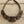 Load image into Gallery viewer, An antique bronze statement necklace featuring a beaded chain and three large, textured skull-shaped center plates, displayed on a rustic, weathered wood background.
