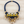 Charger l'image dans la galerie, A statement bib-style necklace featuring a thick navy blue braided cord, gold-tone metal accents, white and yellow fabric panels, and dangling clear faceted crystal beads, displayed on a light wood background.
