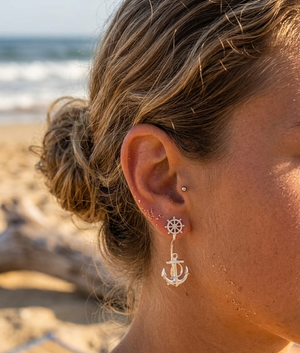 Close-up of a person's ear with earrings on a beach.