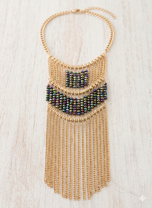 Gold beaded necklace with multicolored beads on a light wooden surface