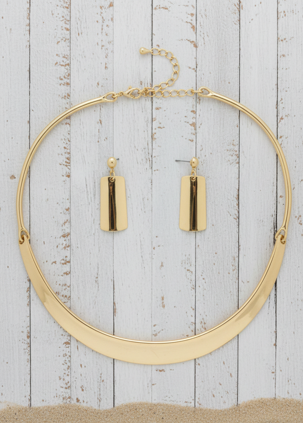 Gold hoop necklace and earrings on a wooden surface