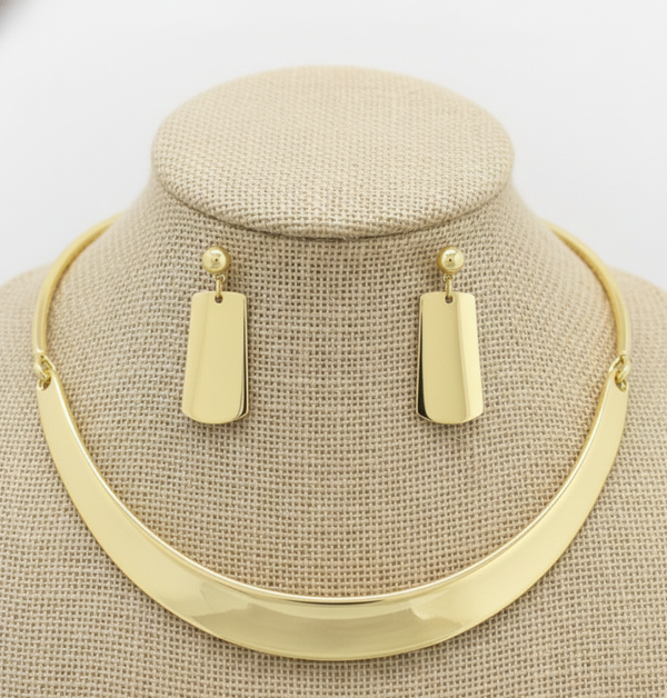 Gold necklace and earrings on a mannequin bust with a white background