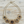 Charger l'image dans la galerie, A gold-toned statement necklace featuring five ornate floral elements with dark centers and small clear rhinestones, displayed on a light wood background.
