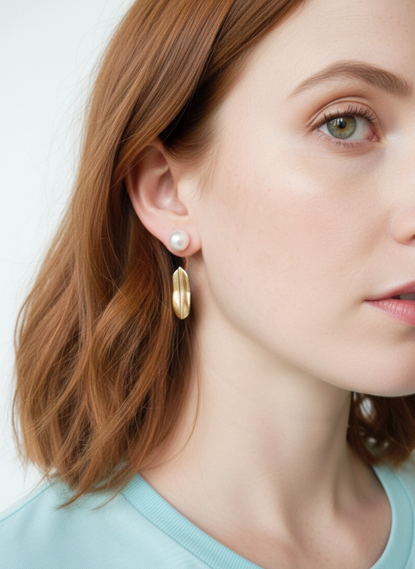 Close-up of a woman wearing gold hoop earrings with a plain background