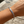 Load image into Gallery viewer, A silver chain bracelet with a polished bar engraved with the word 'GOODLUCK' in black capital letters, shown worn on a person's wrist against a blurred outdoor wooden background.
