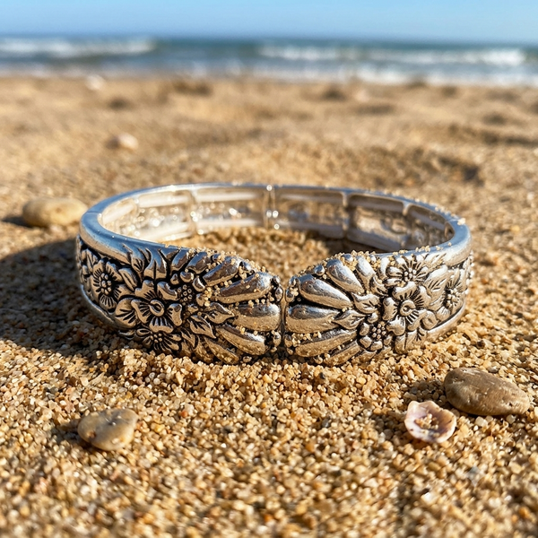 Silver bracelet with floral designs on a sandy beach
