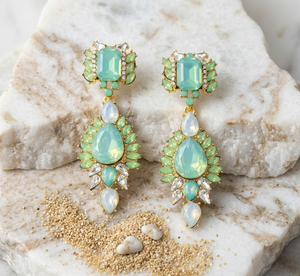 Teal and gold earrings on a textured stone surface