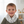 Load image into Gallery viewer, Child wearing a white scarf with black patterns in a room with toys on shelves.
