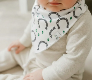 Baby wearing a white bib with black horseshoe patterns