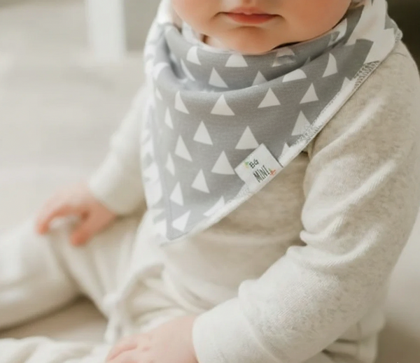 Baby wearing a gray and white triangle patterned bib.